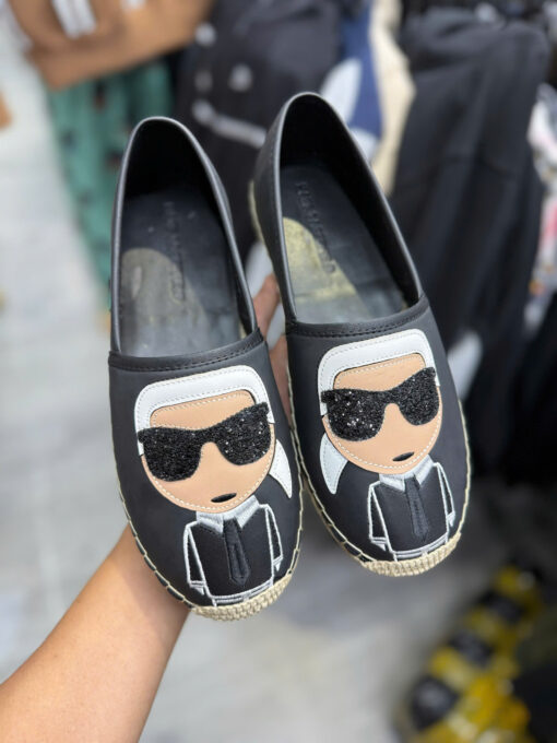 Đôi giày slip-on được thiết kế với phong cách độc đáo, nổi bật nhờ họa tiết nhân vật hoạt hình đeo kính đen cực “cool”. Phần upper làm từ chất liệu mềm mại, tạo cảm giác thoải mái khi mang. Đế cói được may chắc chắn, chống trơn trượt, dễ dàng phối cùng nhiều kiểu trang phục như quần jean, váy hay đồ dạo phố. Đây là lựa chọn hoàn hảo cho những ai yêu thích sự cá tính, trẻ trung và muốn tạo dấu ấn thời trang riêng.